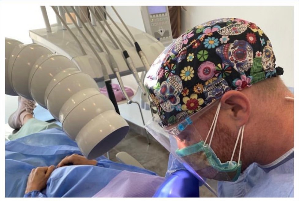 Dentista con equipo de protección y mascarilla de oro